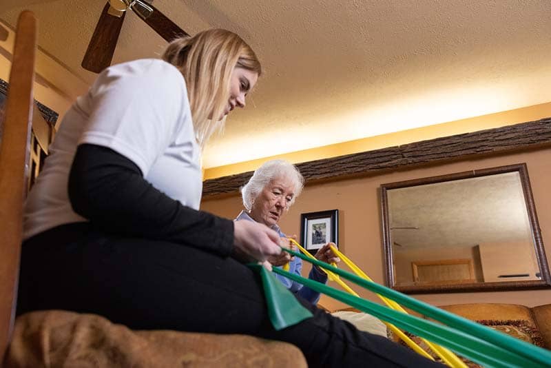 student helping elderly woman with stretch bands