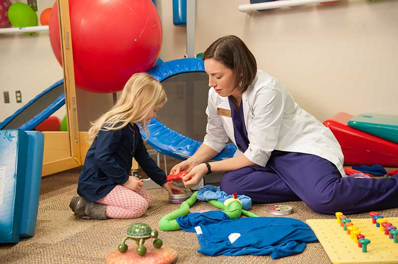 OT helping helping child on floor