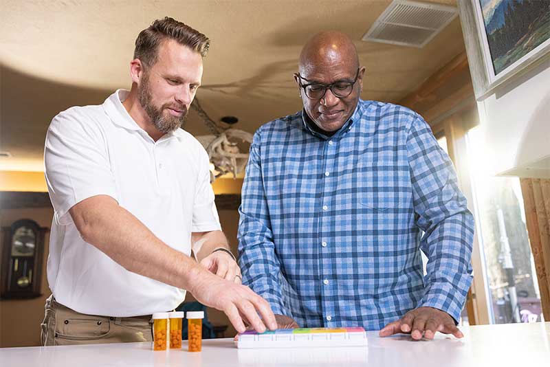 student assisting man with pill containers