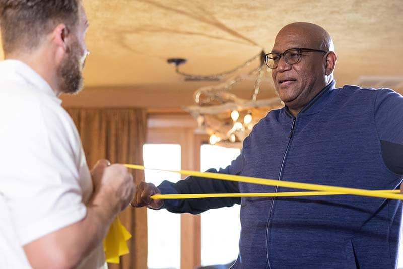 student helping older man with stretch bands