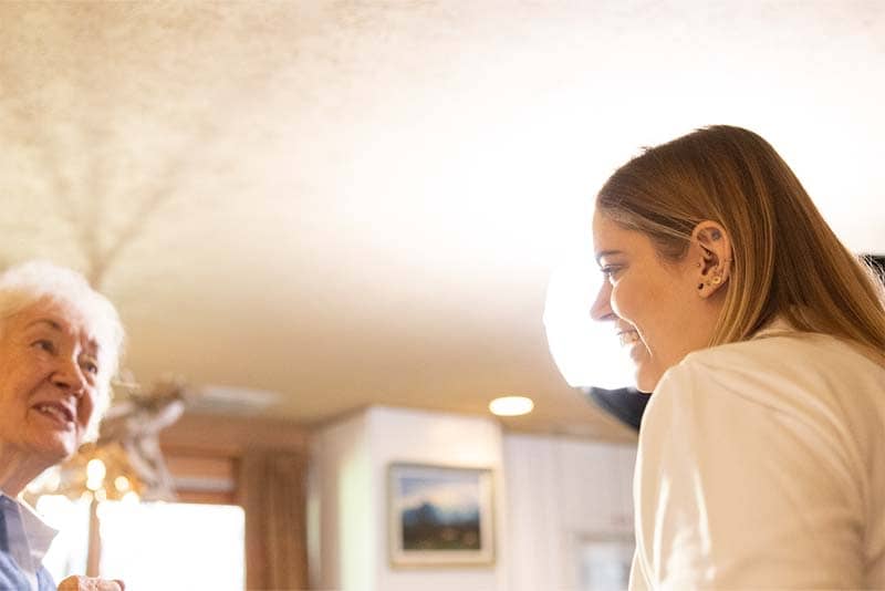 student standing in living room with elderly woman