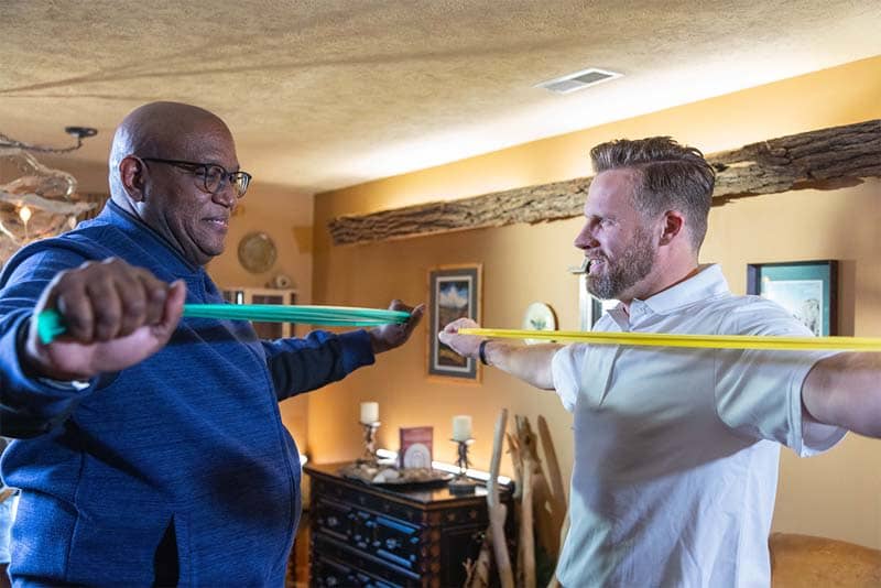 student helping older man with stretch bands