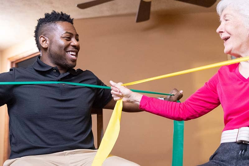 student helping elderly woman with stretch bands