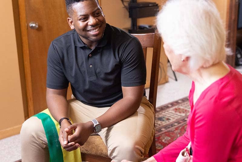 student sitting down with elderly woman