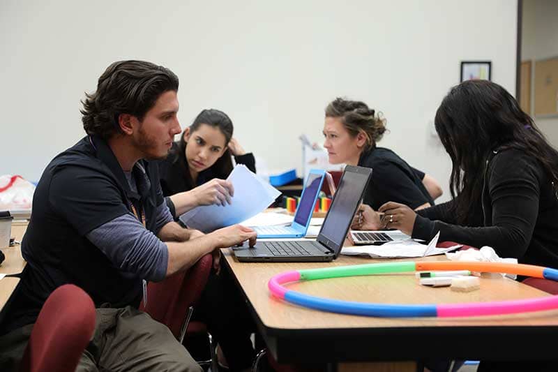 OT students in classroom sitting at desk with computers