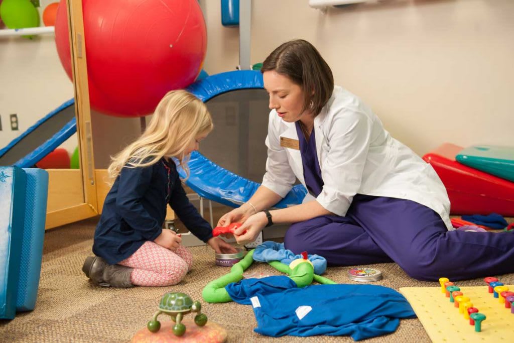 OTA working with child and toys on floor