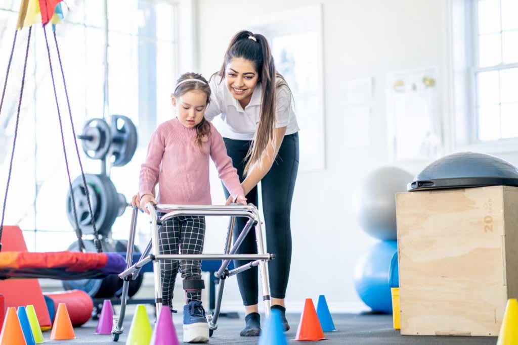 woman helping a child with a walker