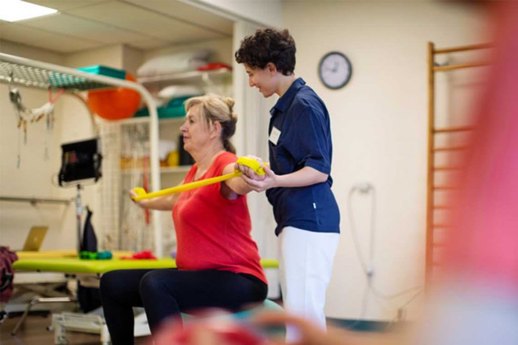 OTA helping patient with stretching bands