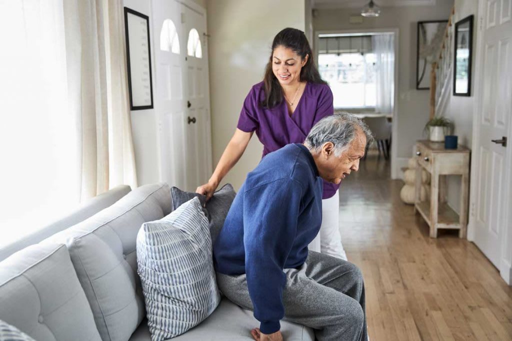 OTA helping patient stand up from couch