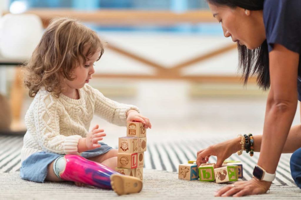 woman on floor with child playing with blocks