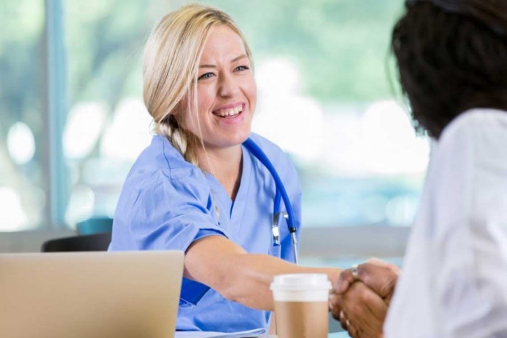 woman in scrubs shaking person's hand