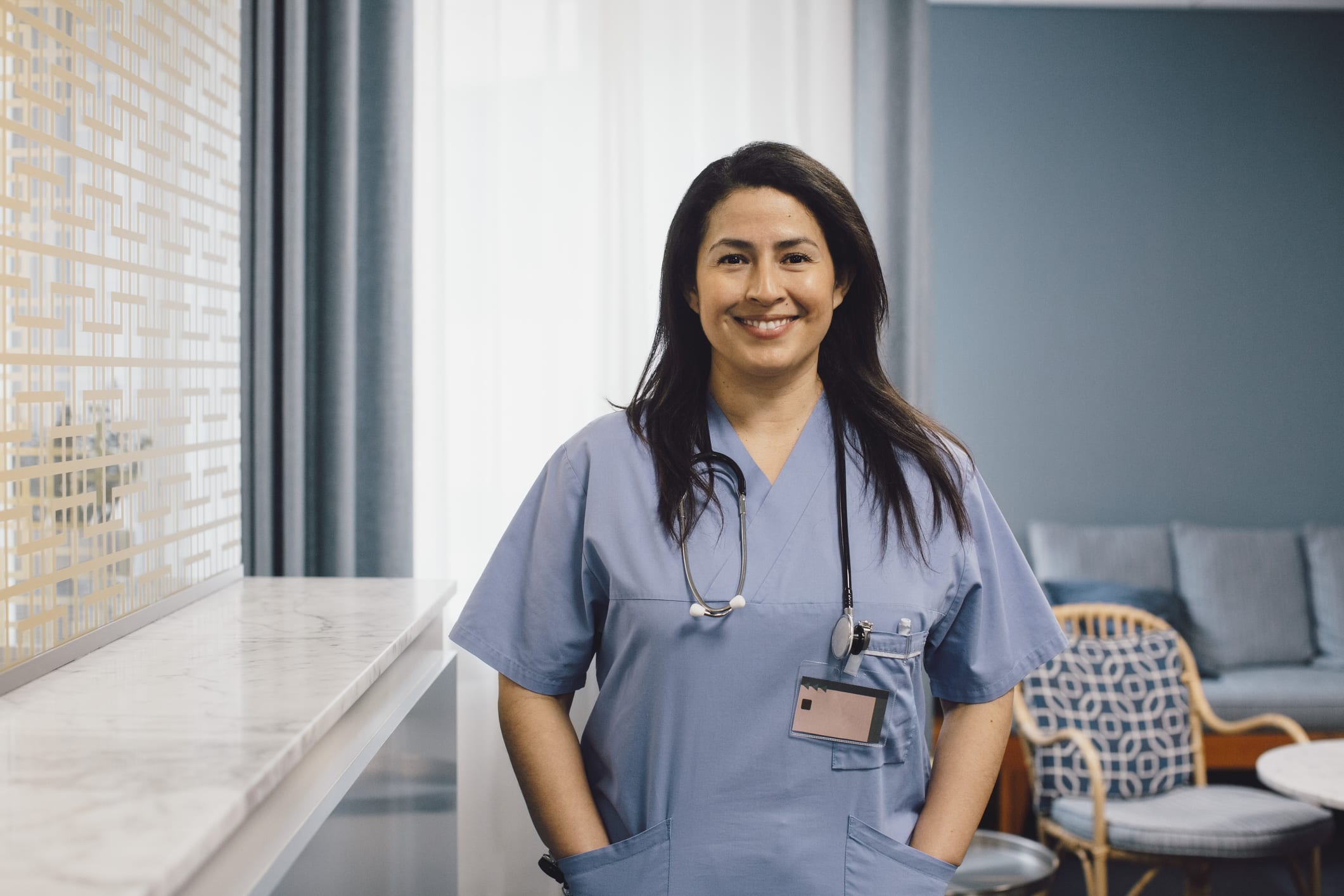 Portrait of smiling female nurse with hands in pockets