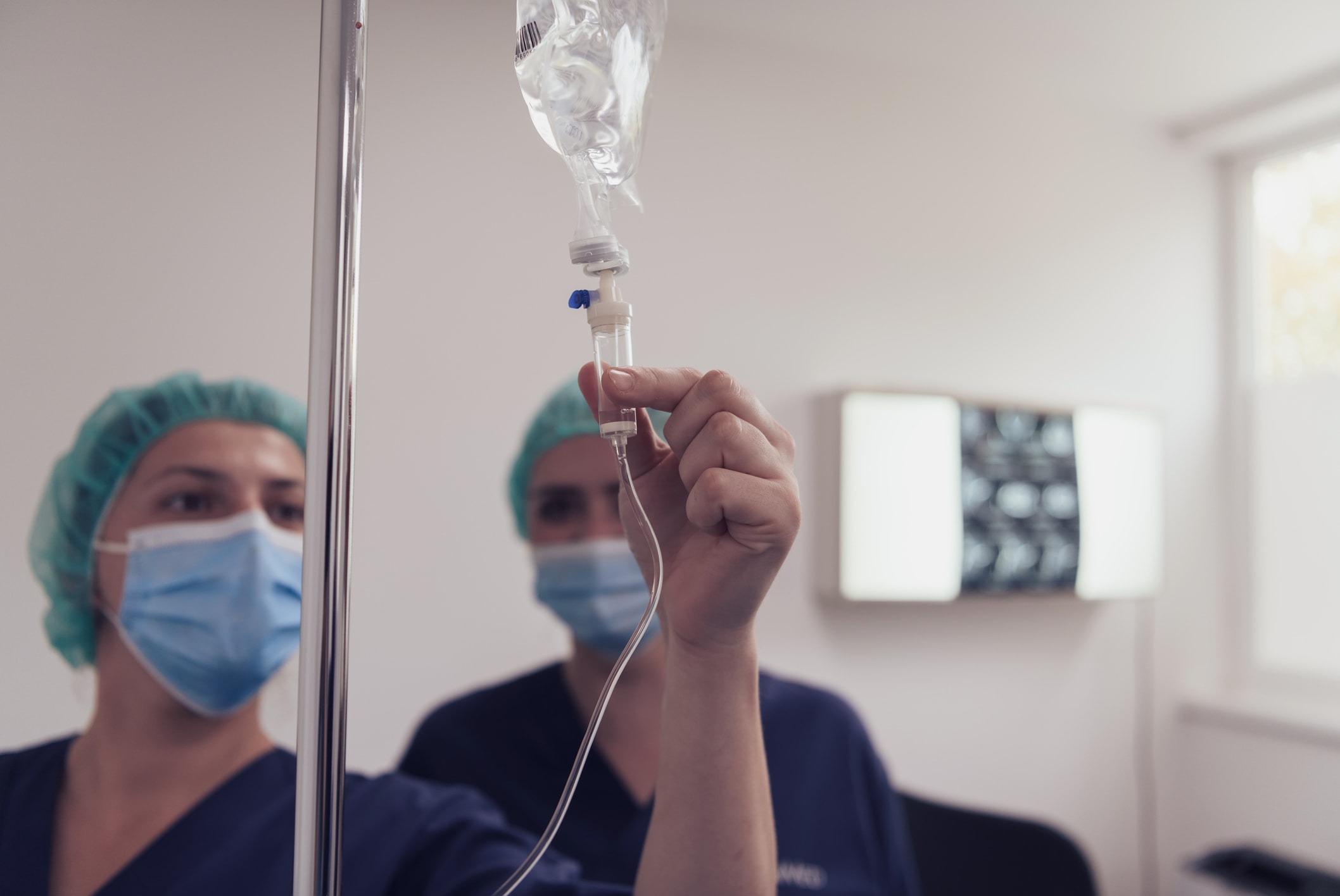 General practitioner holding intravenous drip infusion. Doctor handling IV fluid drip