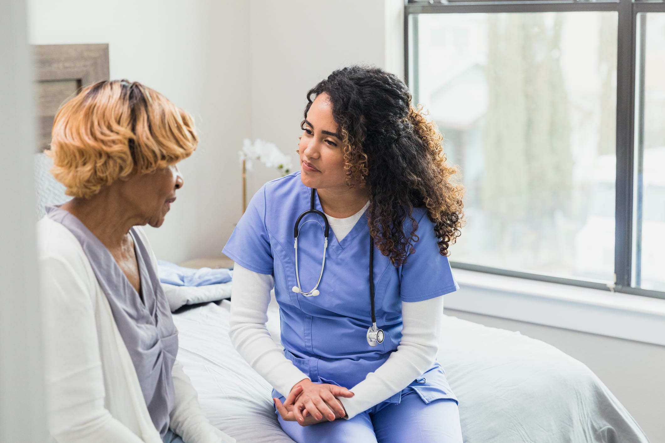 Caring nurse listens to senior patient during home visit