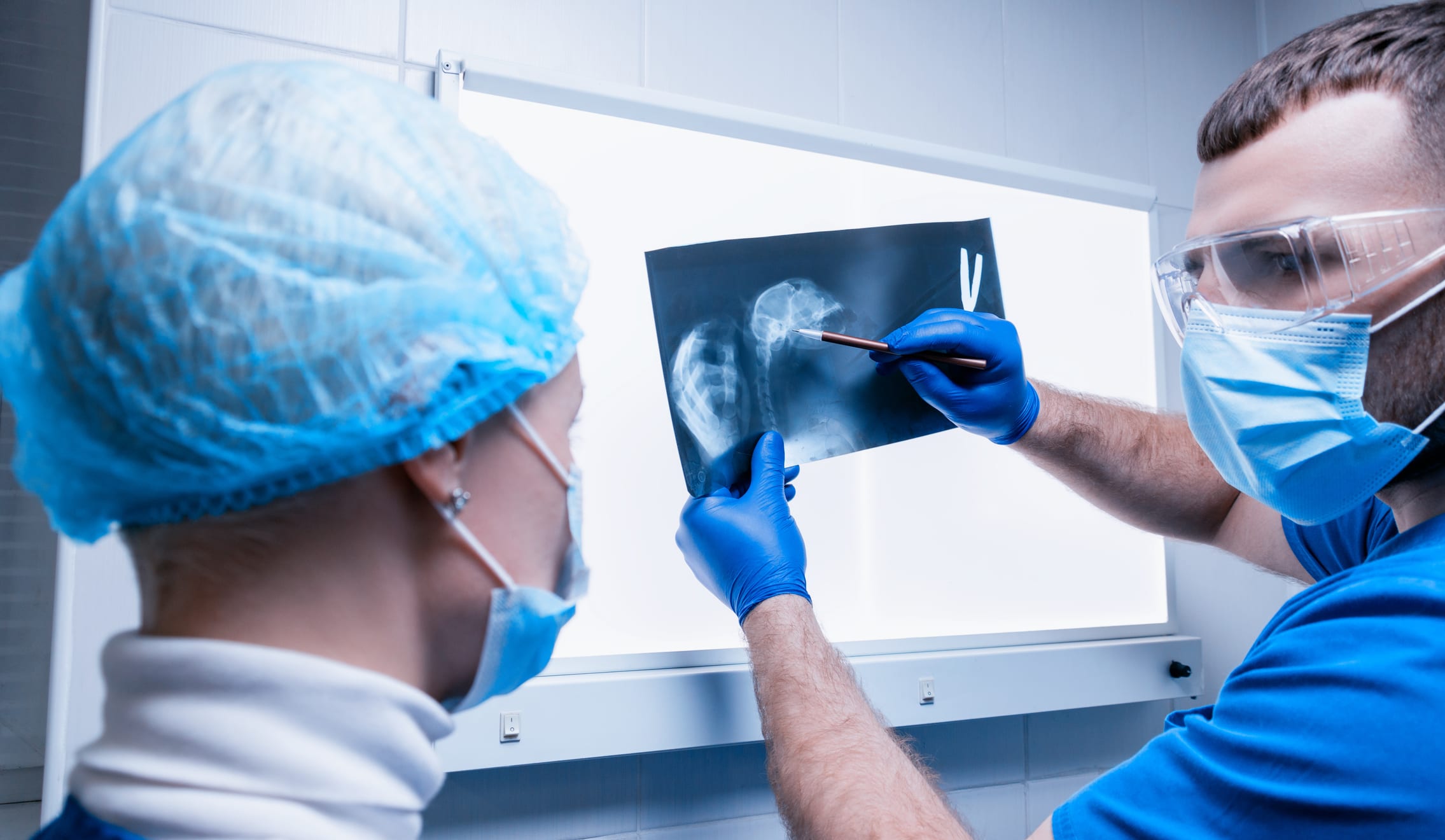 Male doctor and a female nurse stand near a negatoscope and examine an X-ray