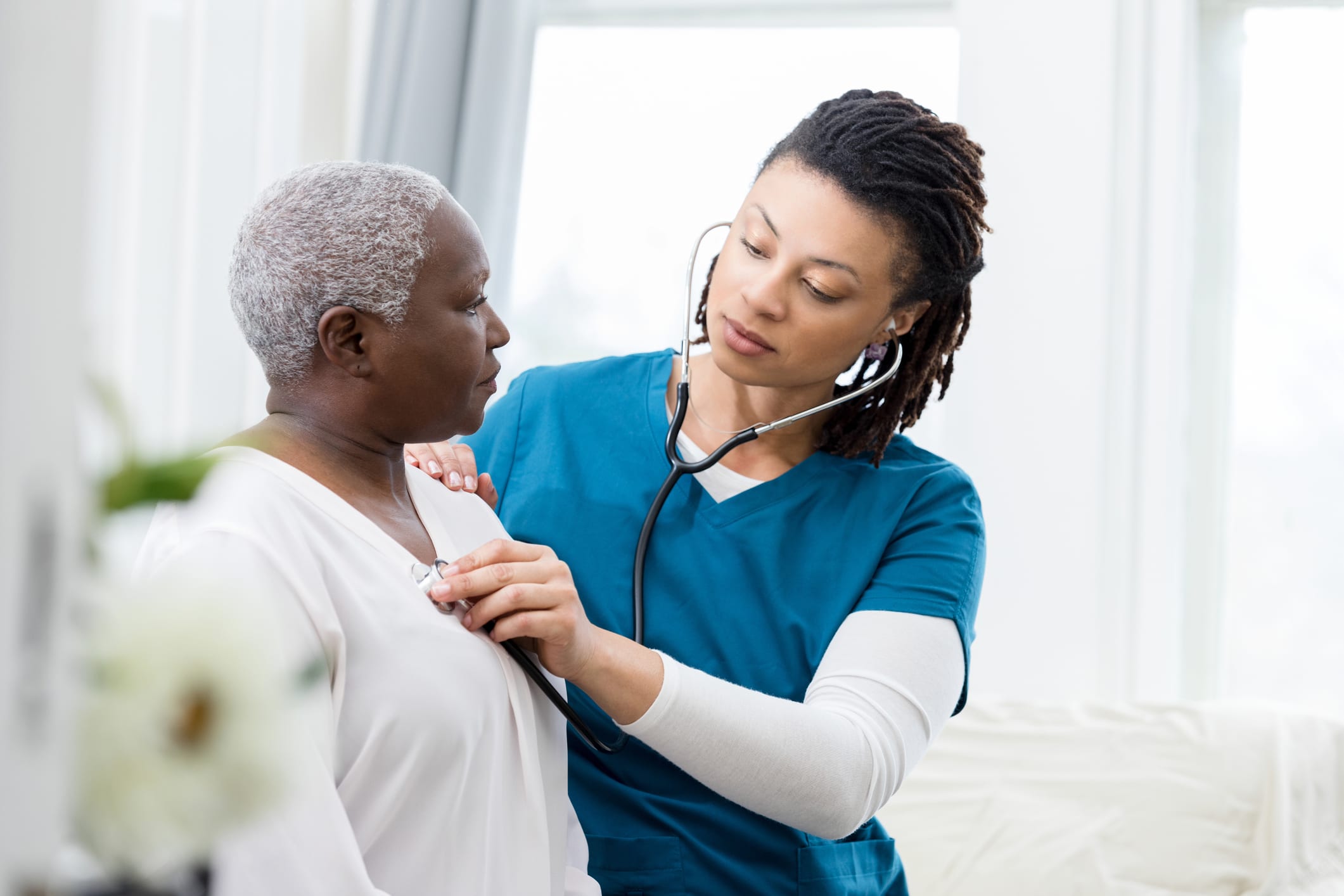 nurse using stethoscope to listen to patient heartbeat