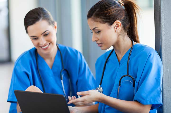 two nurses talking and looking at a computer