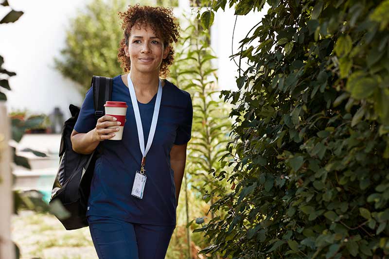 nurse walking outside with coffee