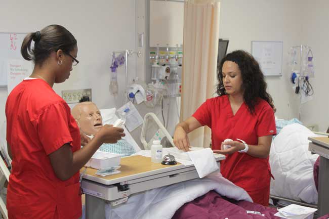 ABSN students working with simulation manikin in lab