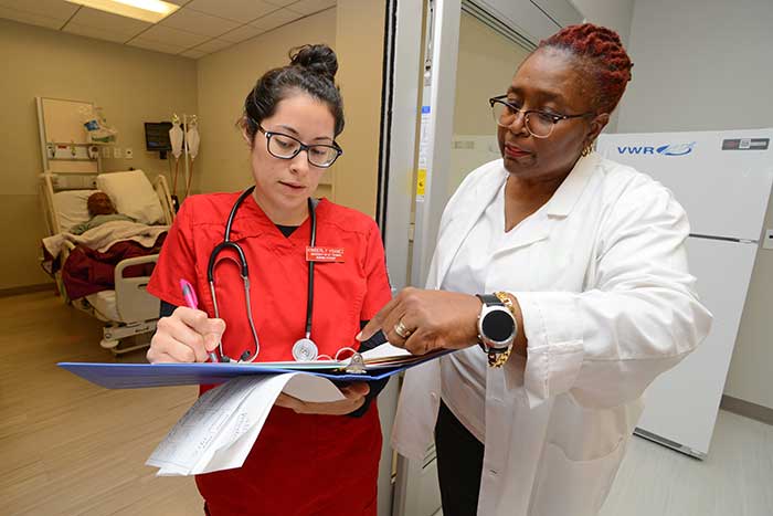 nursing student with binder standing with instructor