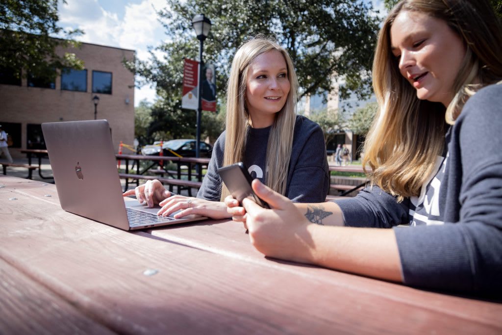 two nursing students sitting together outside at table