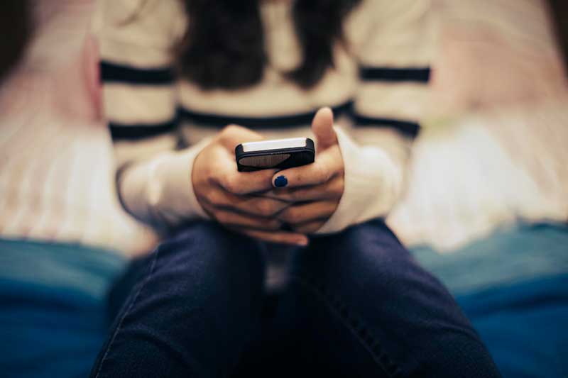 person holding phone while sitting on bed