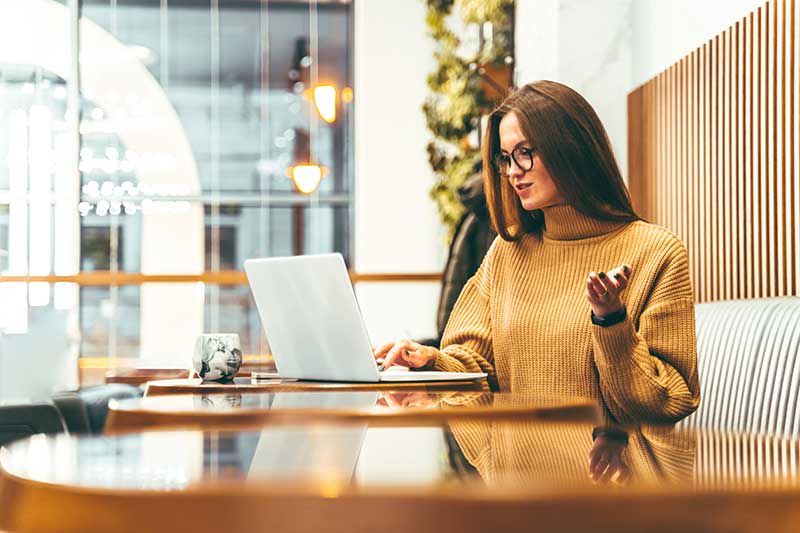 woman sitting at table using laptop