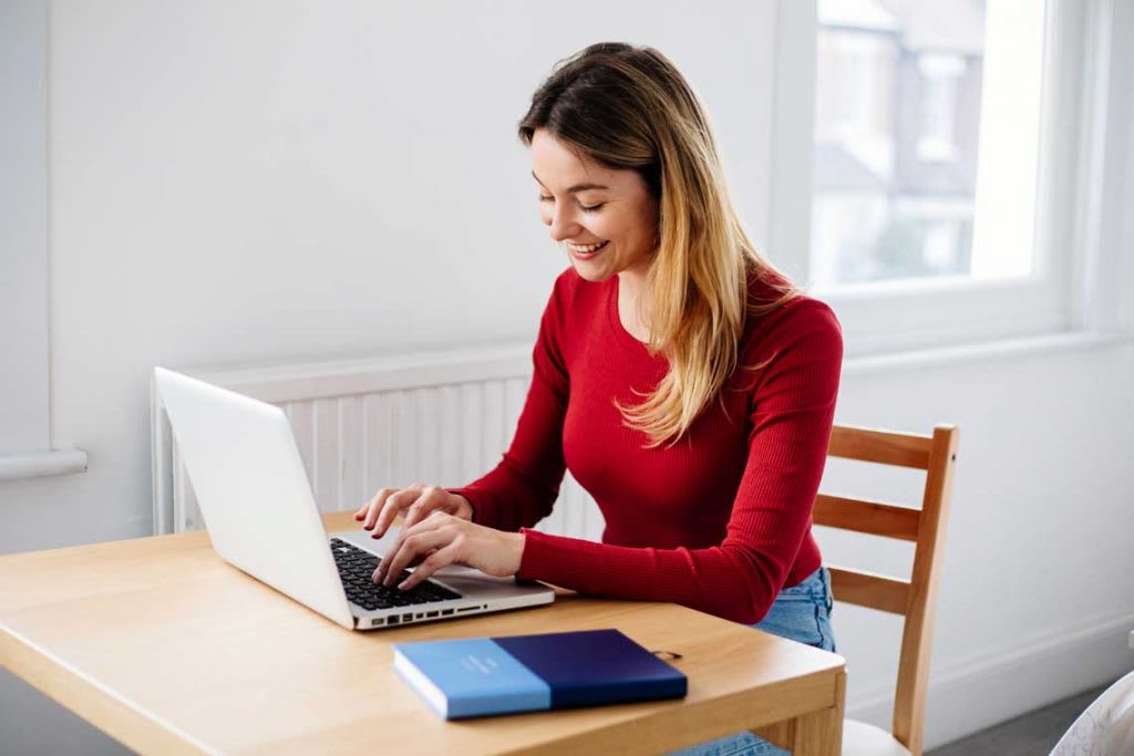 woman in red sweater sitting at desk using laptop