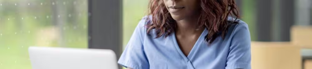 nurse on laptop with stack of textbooks