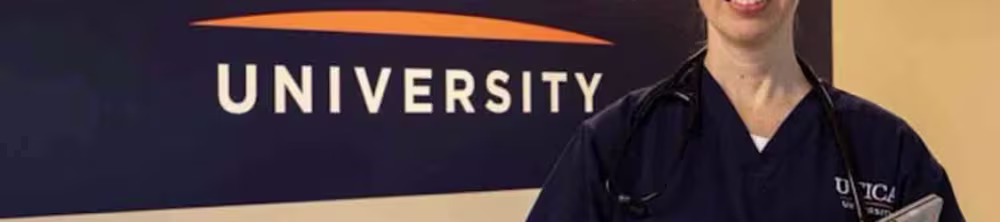 Utica nursing student standing in front of Utica's logo banner
