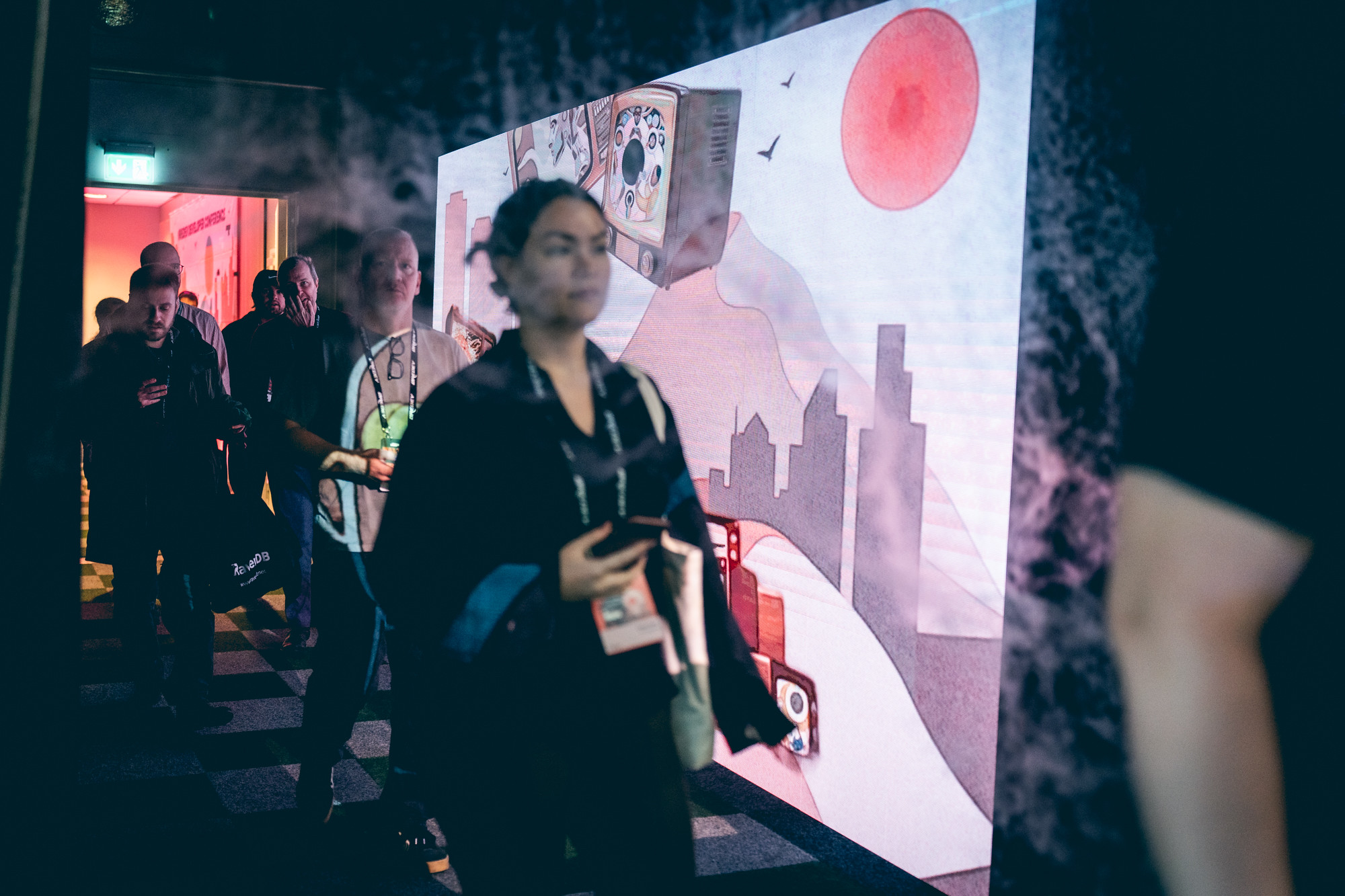 A group of delegates entering Øredev with artwork of a futuristic landscape in the background.
