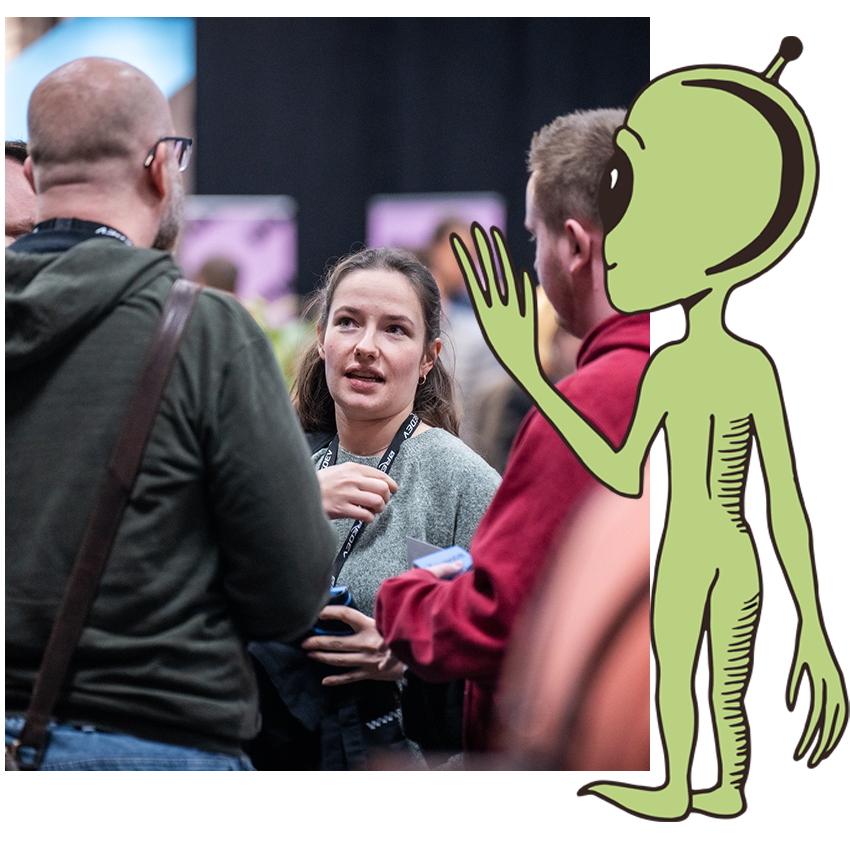 A small alien waiving at a photo of delegates at Øredev