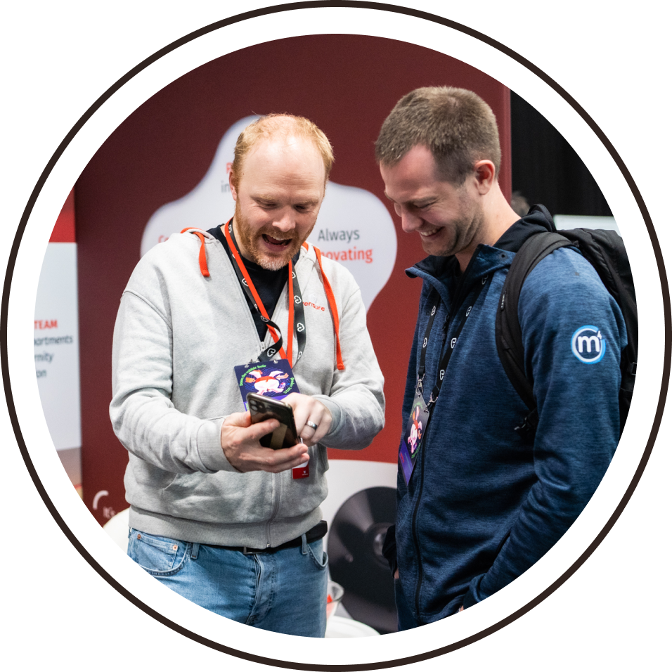 A delegate showing a smiling colleague something on his phone