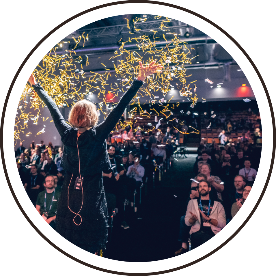 The host at Øredev throwing confetti into the air from the stage.