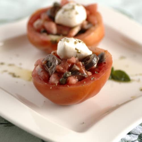 Los tomates crudos rellenos de ovoline búfalo, las aceitunas griegas y orégano