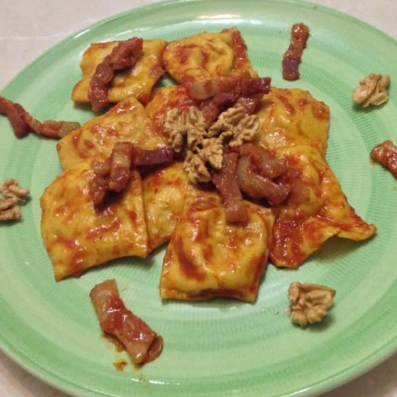 Ravioli con ricotta, achicoria y frutos secos con salsa de tomate y el tocino