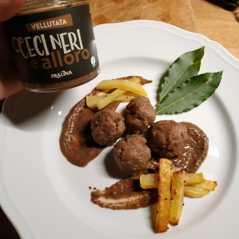 Beef patties on a bed of velvety black chickpeas and bay leaves