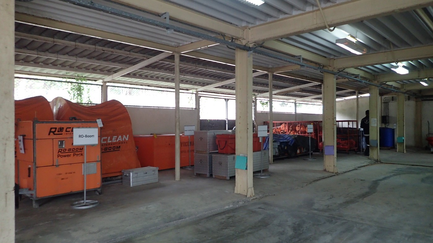 A covered warehouse showcasing various oil spill response tools and equipment, including containment booms, pumps, and skimmers, all neatly organised for quick deployment.