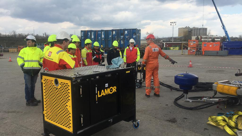 A group of oil spill response professionals conducts an equipment inspection and briefing at an operational site in Bulgaria. The image features Lamor oil spill response equipment and personnel in high-visibility safety gear. 