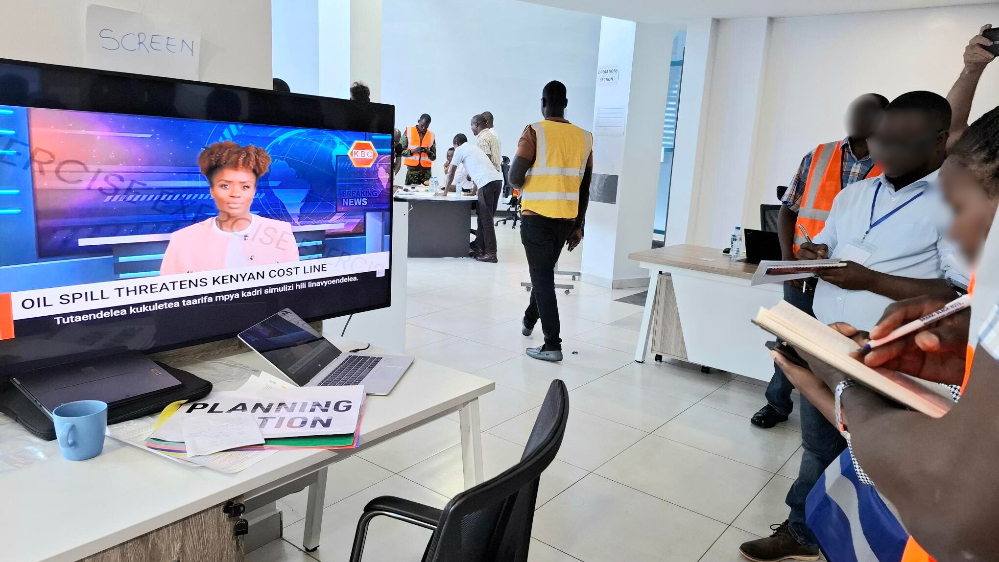 Participants during an oil spill response exercise watch a simulated TV news broadcast reporting an oil spill threatening the Kenyan coastline.