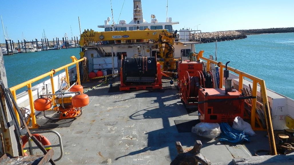 An oil spill response vessel equipped with containment booms, dispersant tanks, and emergency response tools, docked and prepared for offshore oil spill mitigation operations.