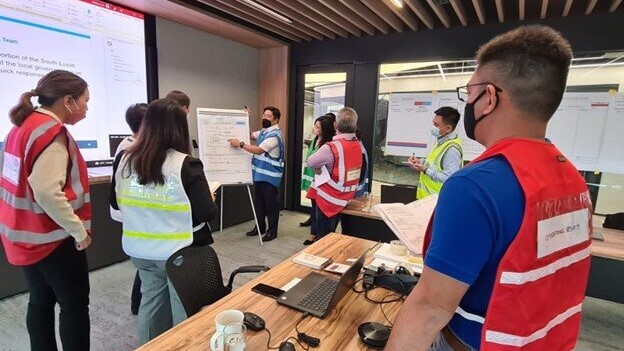 Incident management team conducting an ICS objectives meeting to enhance response strategies, showcasing collaboration and structured communication in crisis management.