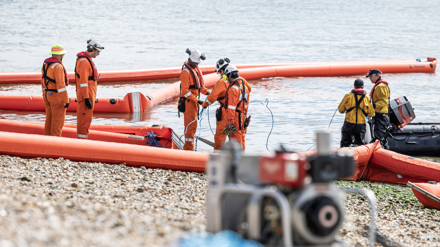 Responders conducting shoreline oil spill containment during a field training exercise