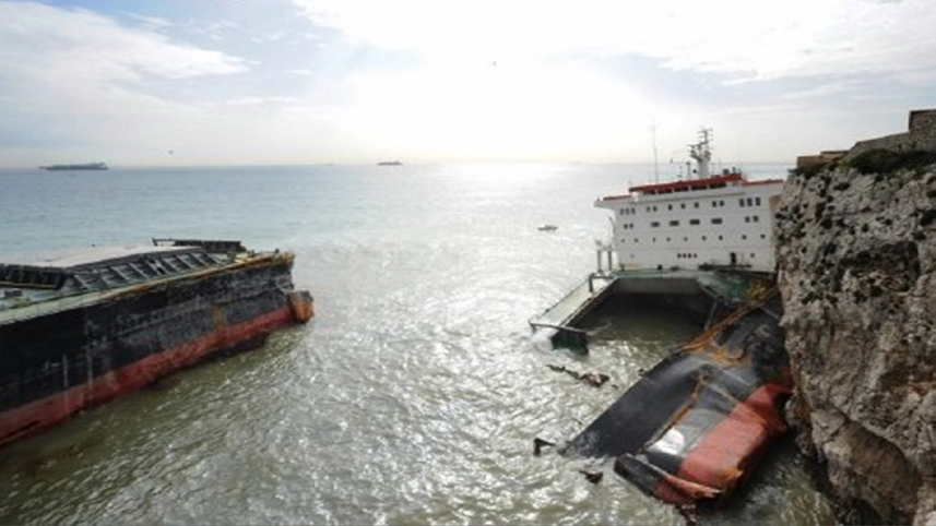 The aftermath of the MV Fedra incident, showing the broken hull of the bulk carrier resting against the rocky coastline of Gibraltar. Sections of the vessel are partially submerged, with evidence of structural collapse. This image reflects the scale of the incident and the challenges of removing the wreck while mitigating environmental impacts.