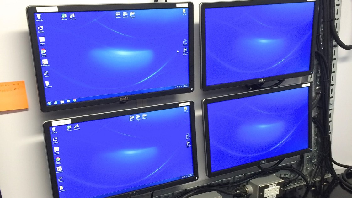 A data processing workstation featuring four mounted screens displaying live readings and analysis from deployed water column monitoring instruments. The setup is used for real-time monitoring and analysis of subsea conditions.