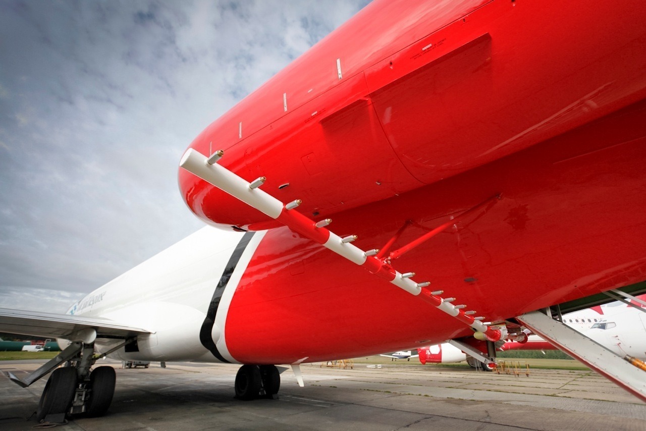 A detailed underside shot of the OSRL Boeing 727, showcasing the TERSUS dispersant spray boom integrated beneath the tail section. Highlights technical modification.