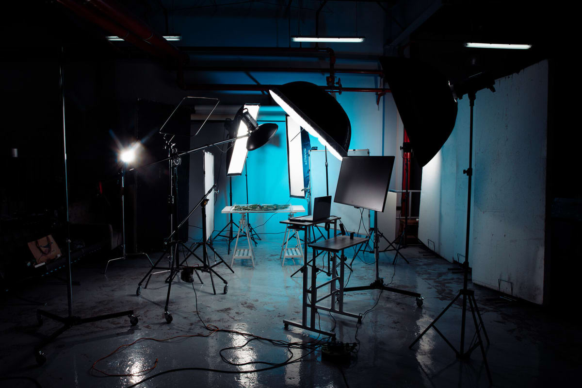 A studio floor at night with lighting stands, softboxes and a monitor set up before a shoot.
