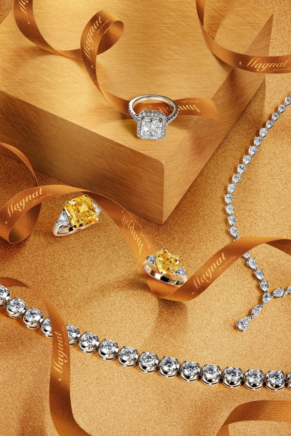Diamond jewellery arranged among coils of gold satin ribbon.