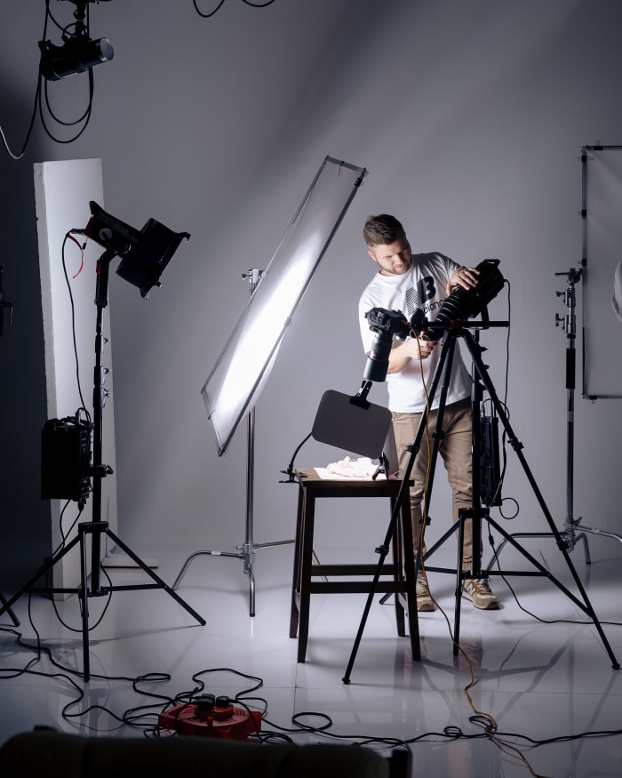 A photographer working behind the camera on a lit studio set.