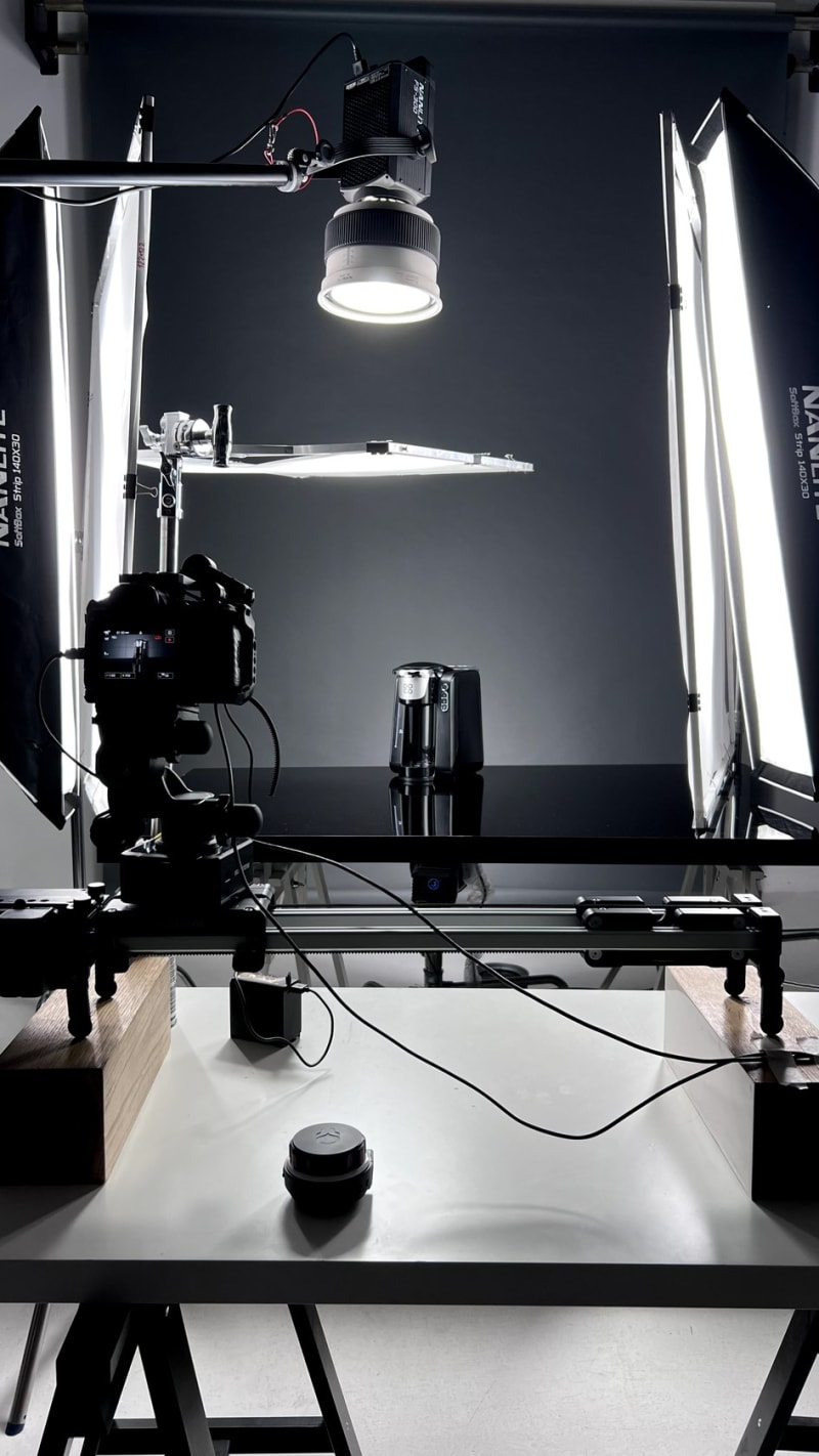 A dark product set: a single spotlight over a small stage, flags shaping the light.